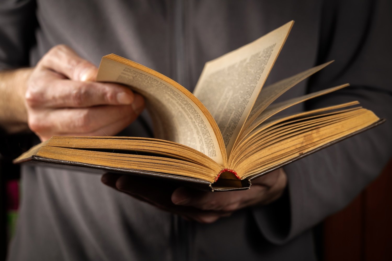 Photo of a person flipping through the pages of an old book.