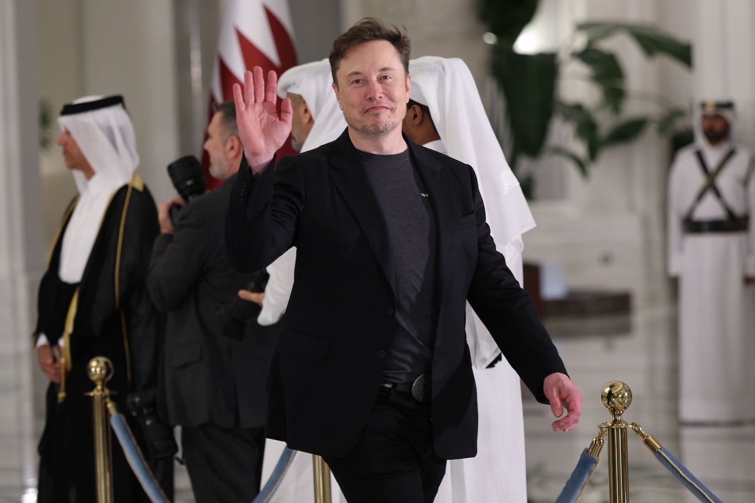 Elon Musk waves as he arrives for a state dinner at the Lusail Palace on May 14, 2025, in Doha, Qatar.