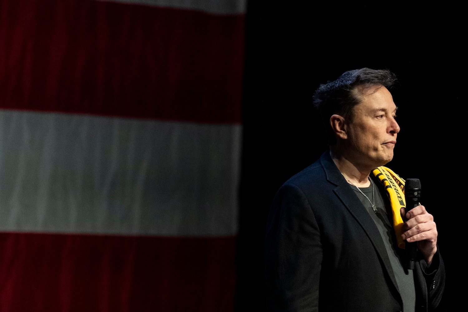 Elon Musk at a Trump rally in Pennsyvlania, holding a shirt over his shoulder.