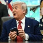 President Donald Trump tries to silence his phone during a press conference in the Oval Office of the White House May 23, 2025 in Washington, DC.
